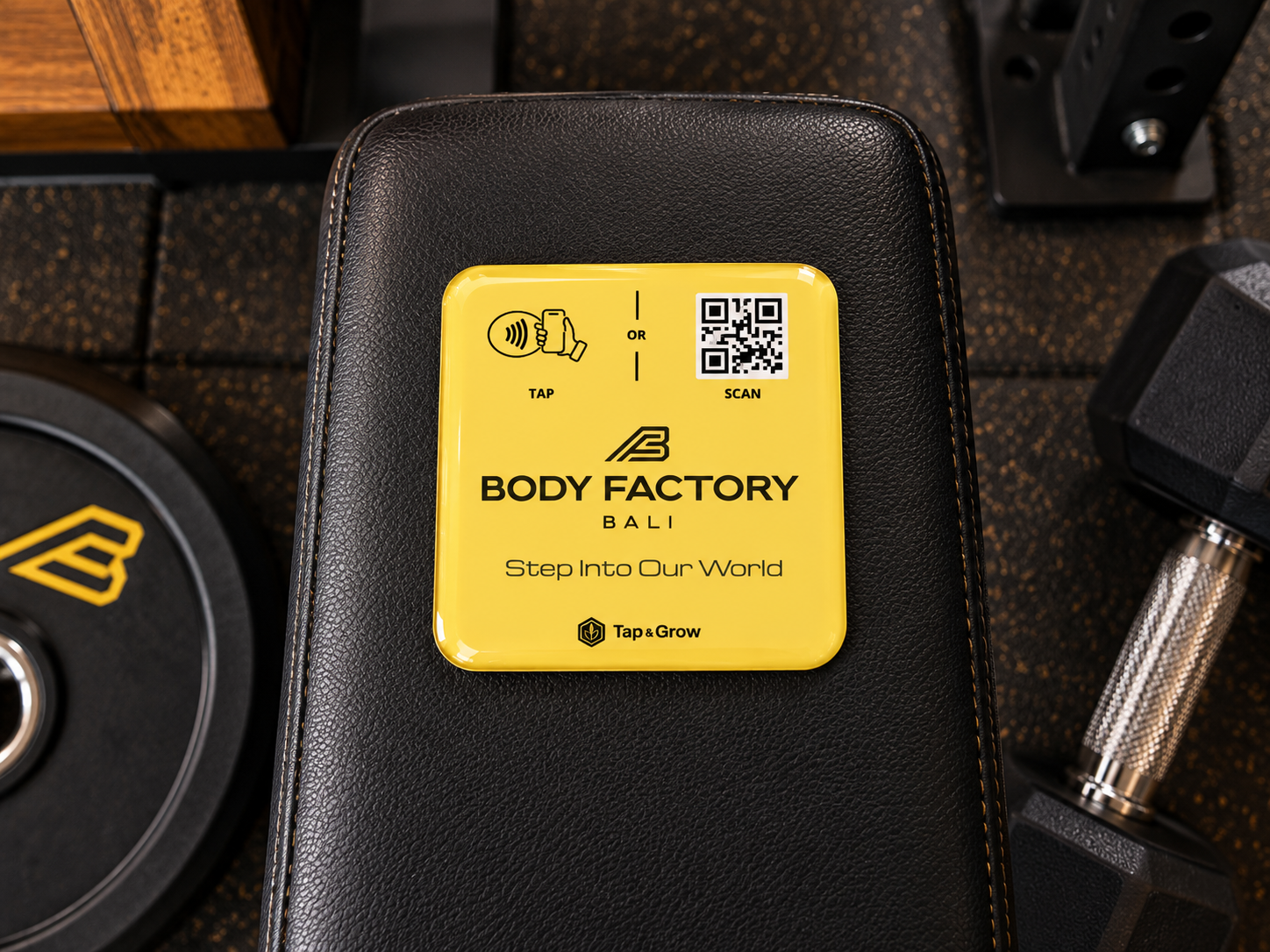 Concept image of a yellow Body Factory Bali NFC and QR piece on a weight bench